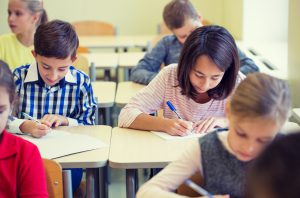 group of school kids writing test in classroom